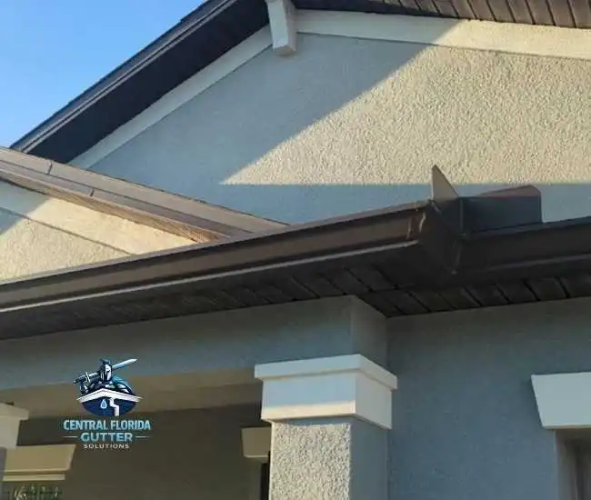 "Dark brown seamless aluminum gutter with custom mitered corner and splash guard installed on a modern stucco home."