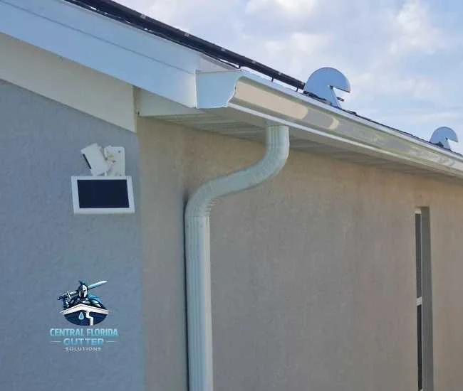 "White 6-inch seamless gutter and downspout installed on a residential home with a solar-powered security camera."