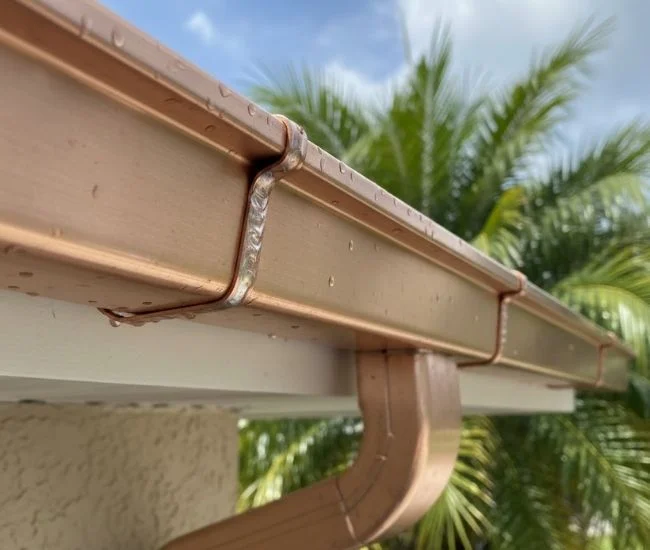Close-up view of soldered copper gutter joint during installation, showing precise seam work, reinforced hanger spacing, and clean alignment along a residential fascia board in Polk County.